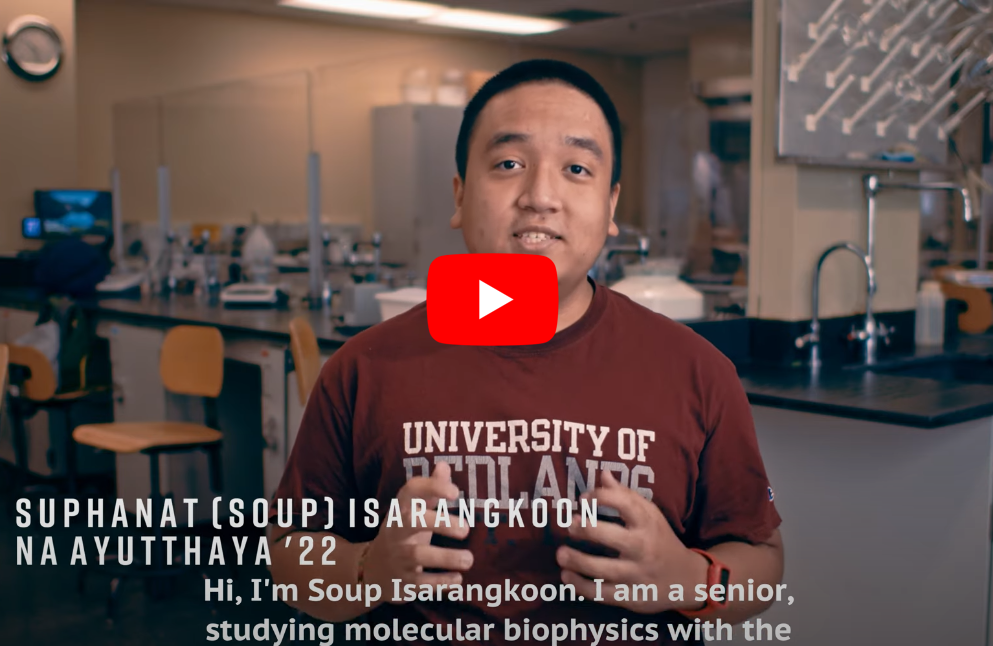 Photo of Soup wearing a red shirt speaking in a lab in a video by the University of Redlands